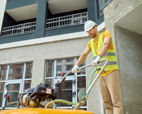 effort-fatigue-young-adult-tired-man-protective-helmet-bright-vest-with-special-equipment-working-construction-site-against-background-new-building
